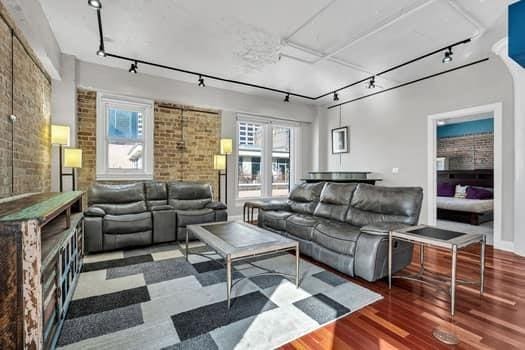 909 Lafayette St Unit 6, New Orleans, LA 70113 - living room featuring track lighting, wood finished floors, and brick wall