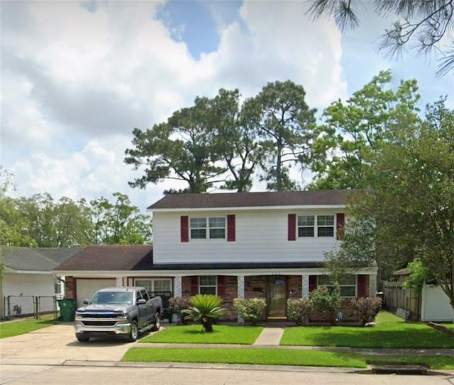 traditional-style home featuring an attached garage, fence, a front lawn, and concrete driveway