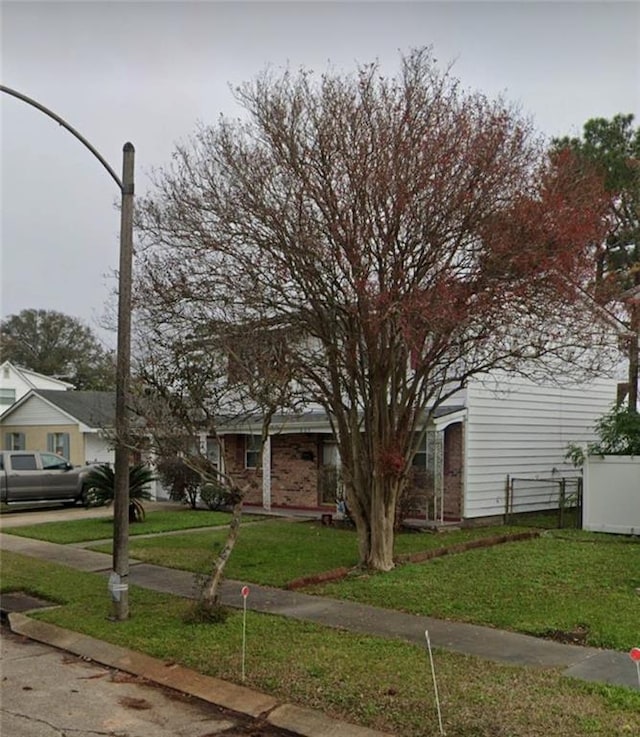 view of property hidden behind natural elements with driveway and a front yard