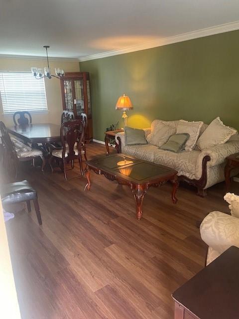 living area with crown molding, a notable chandelier, and wood finished floors