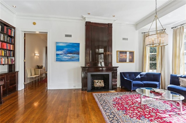 living area with ornamental molding, a large fireplace, baseboards, and wood finished floors