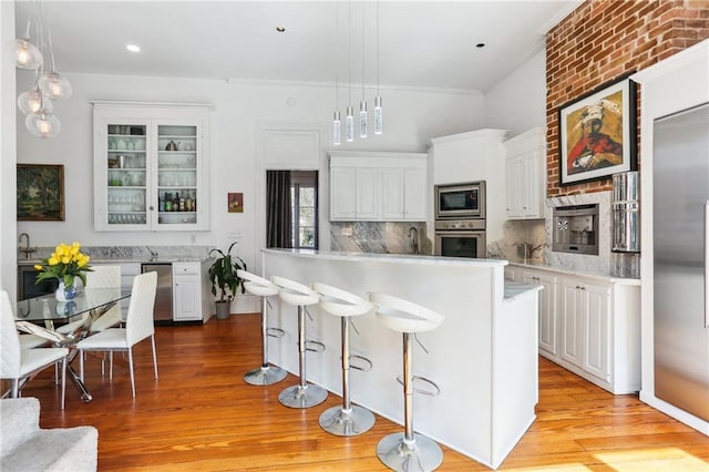 kitchen with a kitchen bar, glass insert cabinets, white cabinets, and built in appliances