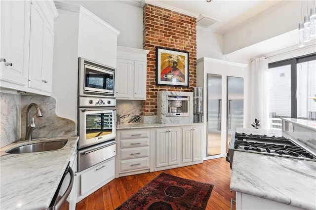 kitchen with built in appliances, a warming drawer, a sink, and decorative backsplash