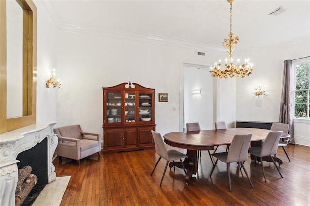 dining space featuring visible vents, a chandelier, dark wood-type flooring, and ornamental molding