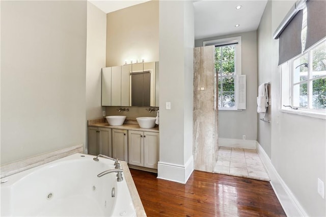 bathroom with plenty of natural light, a sink, and a tub with jets