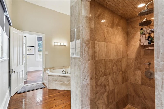 full bath featuring tiled shower, a garden tub, hardwood / wood-style flooring, and baseboards