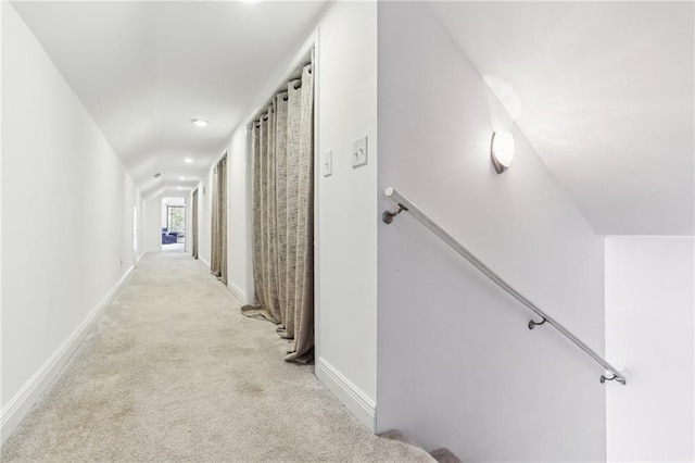 hall featuring baseboards, light carpet, and an upstairs landing