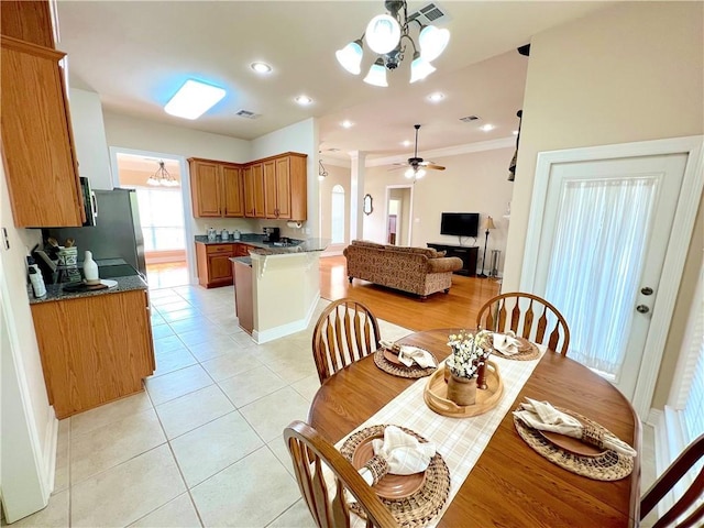 dining space featuring ceiling fan with notable chandelier, visible vents, crown molding, and light tile patterned flooring