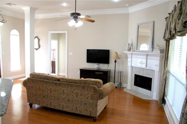 living area featuring a fireplace, wood finished floors, visible vents, and crown molding