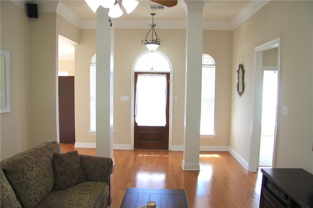 foyer entrance with ornamental molding, light wood-style floors, visible vents, and ornate columns