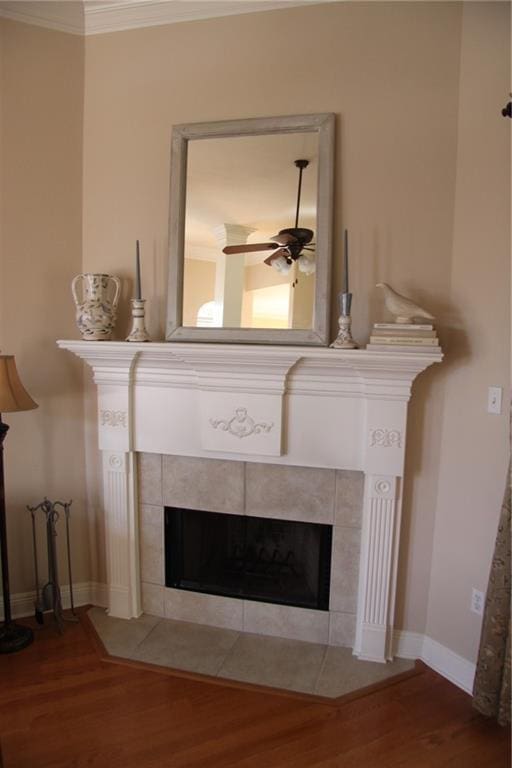 room details with a ceiling fan, a tile fireplace, crown molding, and wood finished floors