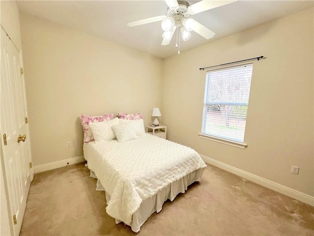 bedroom with a ceiling fan, light carpet, and baseboards