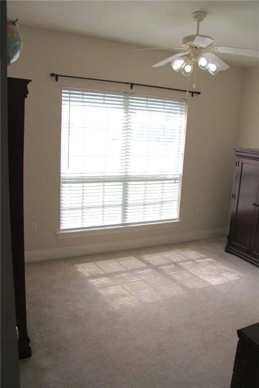 interior space featuring light carpet, baseboards, and multiple windows