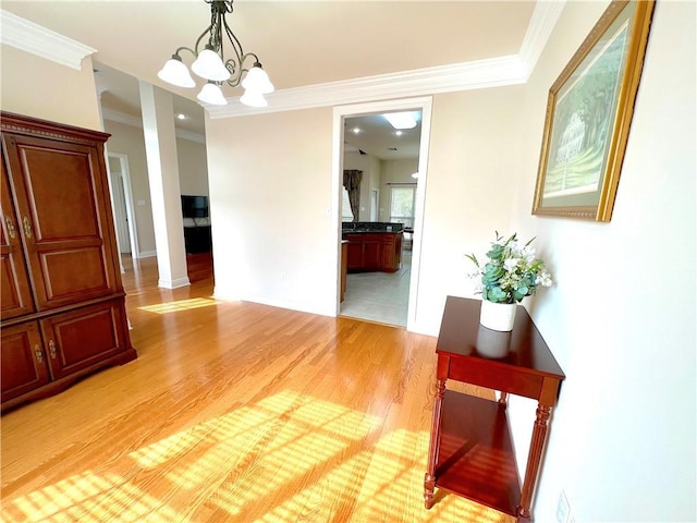 unfurnished dining area featuring light wood-style flooring, ornamental molding, and a notable chandelier