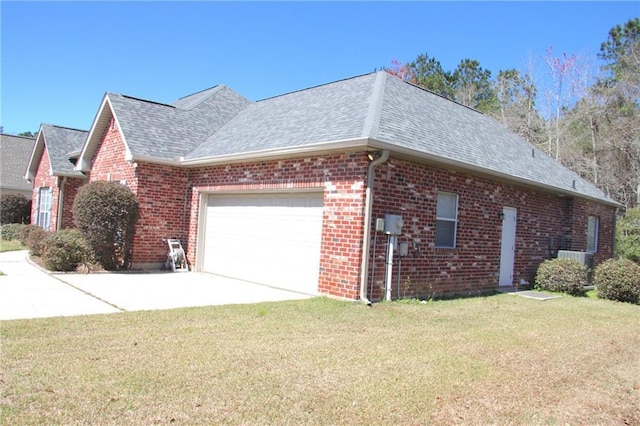 view of side of home featuring a shingled roof, brick siding, a lawn, and an attached garage