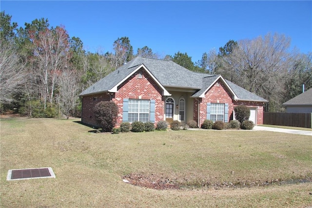 single story home featuring a garage, brick siding, fence, and a front lawn