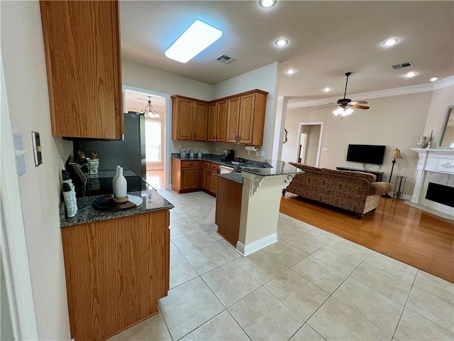 kitchen with open floor plan, a peninsula, visible vents, and brown cabinets