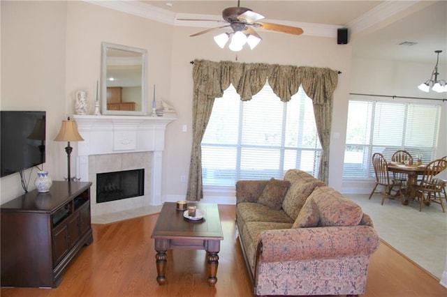 living room with light wood finished floors, a fireplace, visible vents, and crown molding