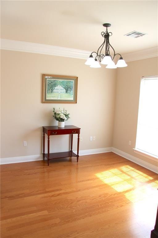 interior space featuring ornamental molding, light wood-type flooring, visible vents, and baseboards