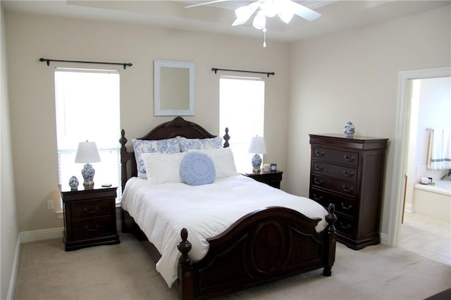 bedroom featuring light carpet, ceiling fan, ensuite bath, and baseboards