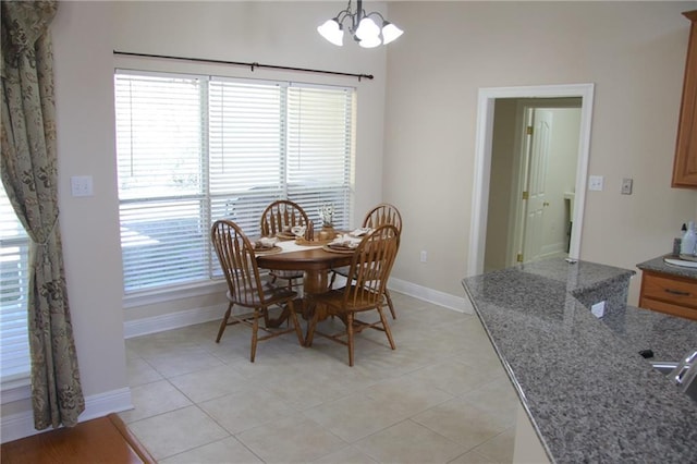 dining room with a wealth of natural light, light tile patterned flooring, a notable chandelier, and baseboards