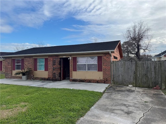 single story home with a shingled roof, fence, a front lawn, and brick siding