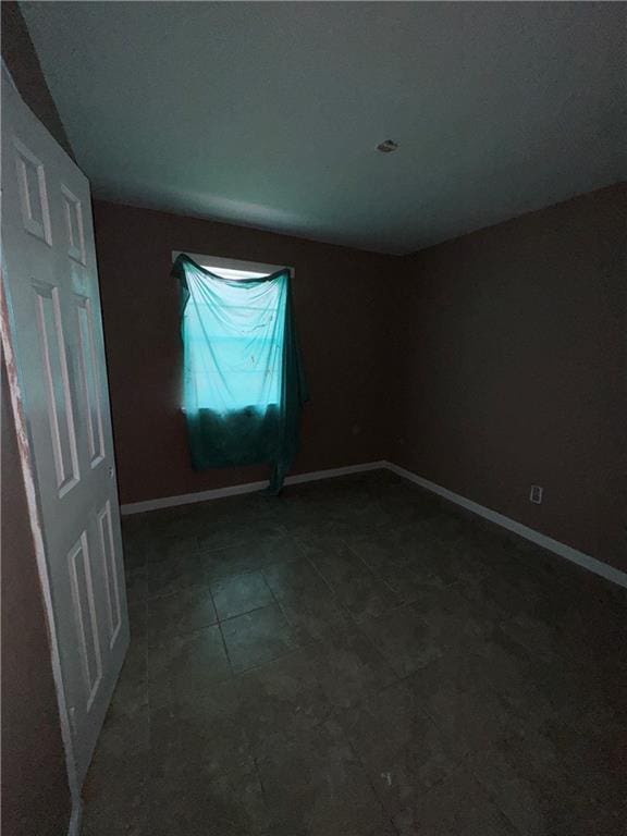 empty room with dark tile patterned floors and baseboards