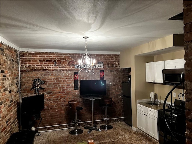 bar featuring black gas range, fridge, stainless steel microwave, and a textured ceiling