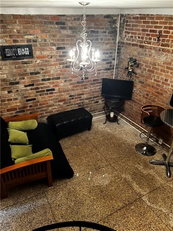 living room with brick wall, granite finish floor, and a chandelier