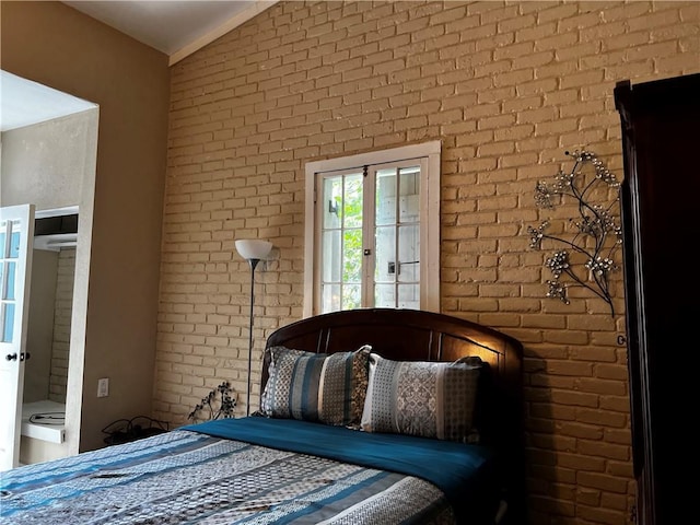 unfurnished bedroom with access to exterior, lofted ceiling, and brick wall