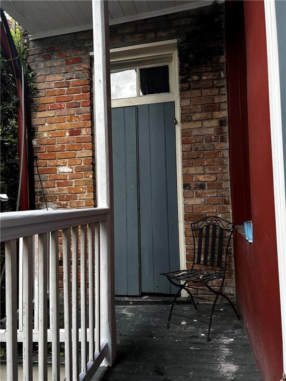 view of exterior entry with covered porch, brick siding, and board and batten siding