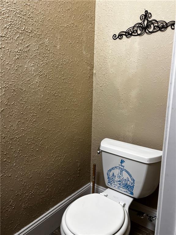 bathroom featuring a textured wall and toilet