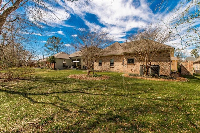 rear view of house featuring a lawn and brick siding