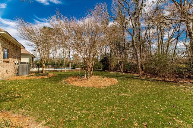 view of yard with fence, central AC unit, and an outdoor pool