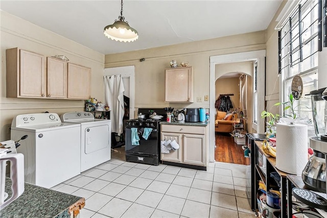 laundry area with arched walkways, laundry area, light tile patterned floors, and separate washer and dryer