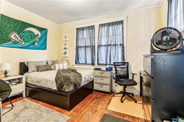 bedroom featuring ornamental molding and wood finished floors