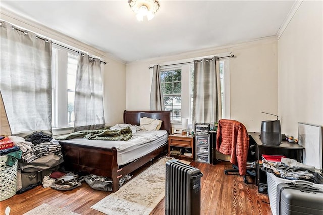 bedroom featuring ornamental molding, radiator heating unit, and wood finished floors