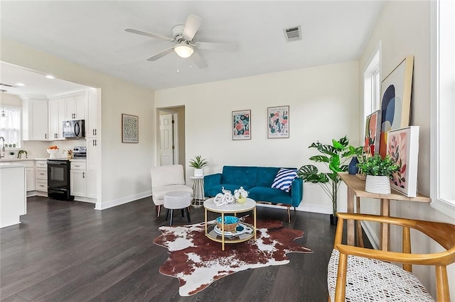 living room featuring ceiling fan, dark wood-type flooring, visible vents, and baseboards