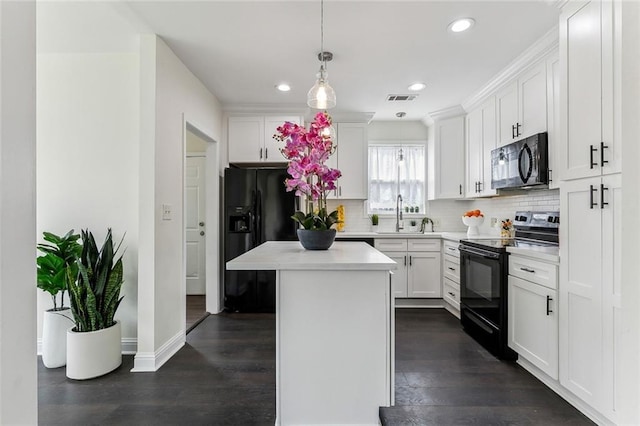 kitchen featuring black appliances, a kitchen island, visible vents, and white cabinets