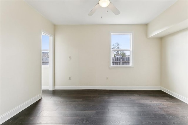 empty room with a ceiling fan, baseboards, and dark wood-type flooring