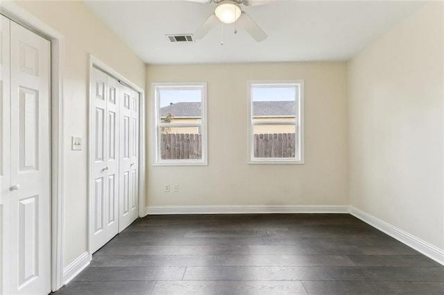 unfurnished bedroom featuring visible vents, dark wood finished floors, baseboards, and ceiling fan