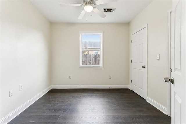 spare room with ceiling fan, dark wood-style flooring, visible vents, and baseboards