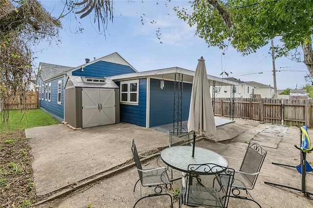 back of property featuring an outbuilding, a storage shed, a patio area, and a fenced backyard