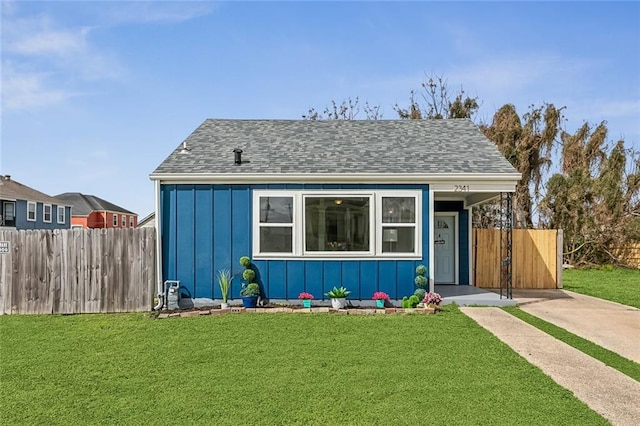 bungalow featuring a shingled roof, fence, a front lawn, and board and batten siding