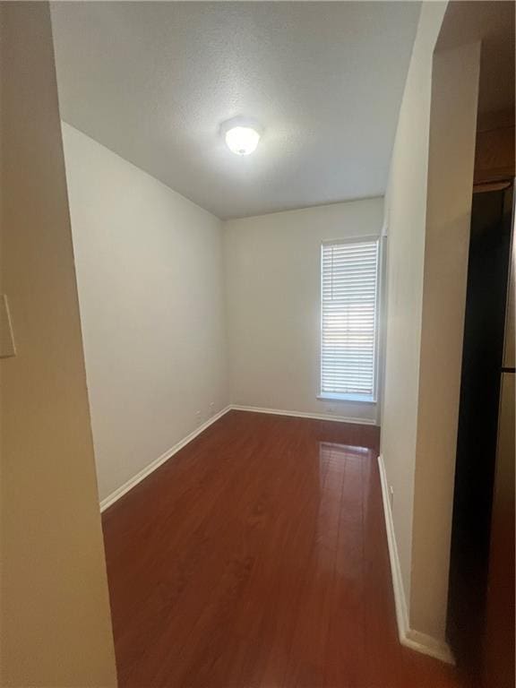 spare room featuring wood finished floors and baseboards