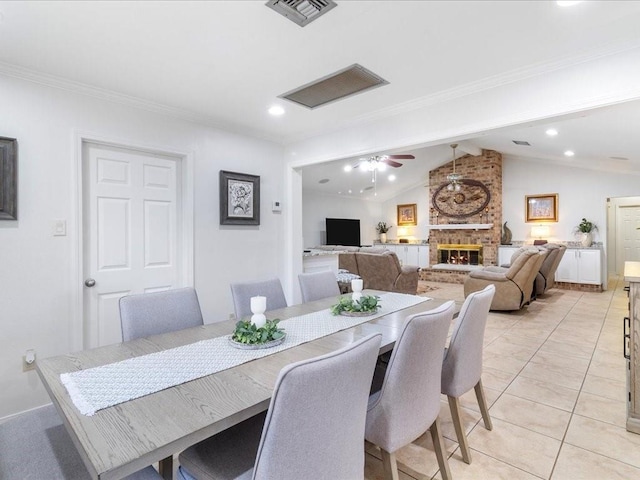 dining area featuring visible vents, a ceiling fan, vaulted ceiling with beams, a fireplace, and light tile patterned flooring