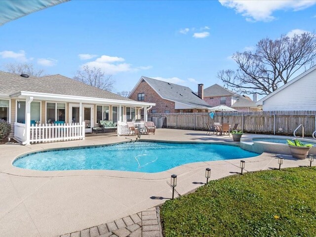 view of pool featuring a pool with connected hot tub, a patio, and fence