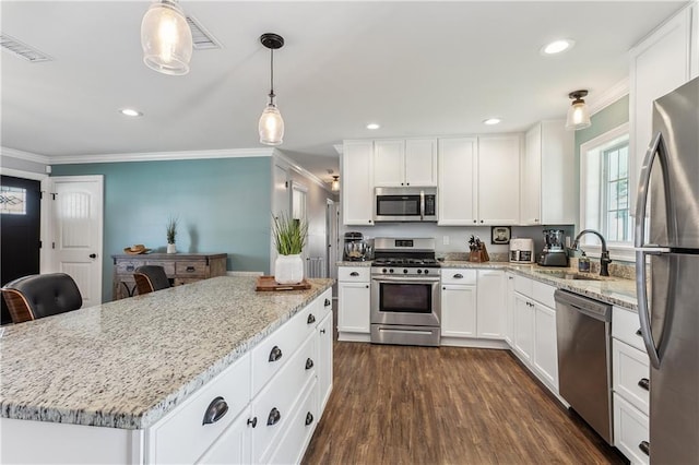 kitchen with dark wood-style floors, appliances with stainless steel finishes, a sink, and ornamental molding