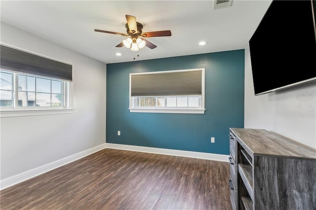 spare room with ceiling fan, baseboards, visible vents, and dark wood finished floors