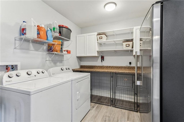 washroom featuring light wood-type flooring, cabinet space, and washing machine and dryer